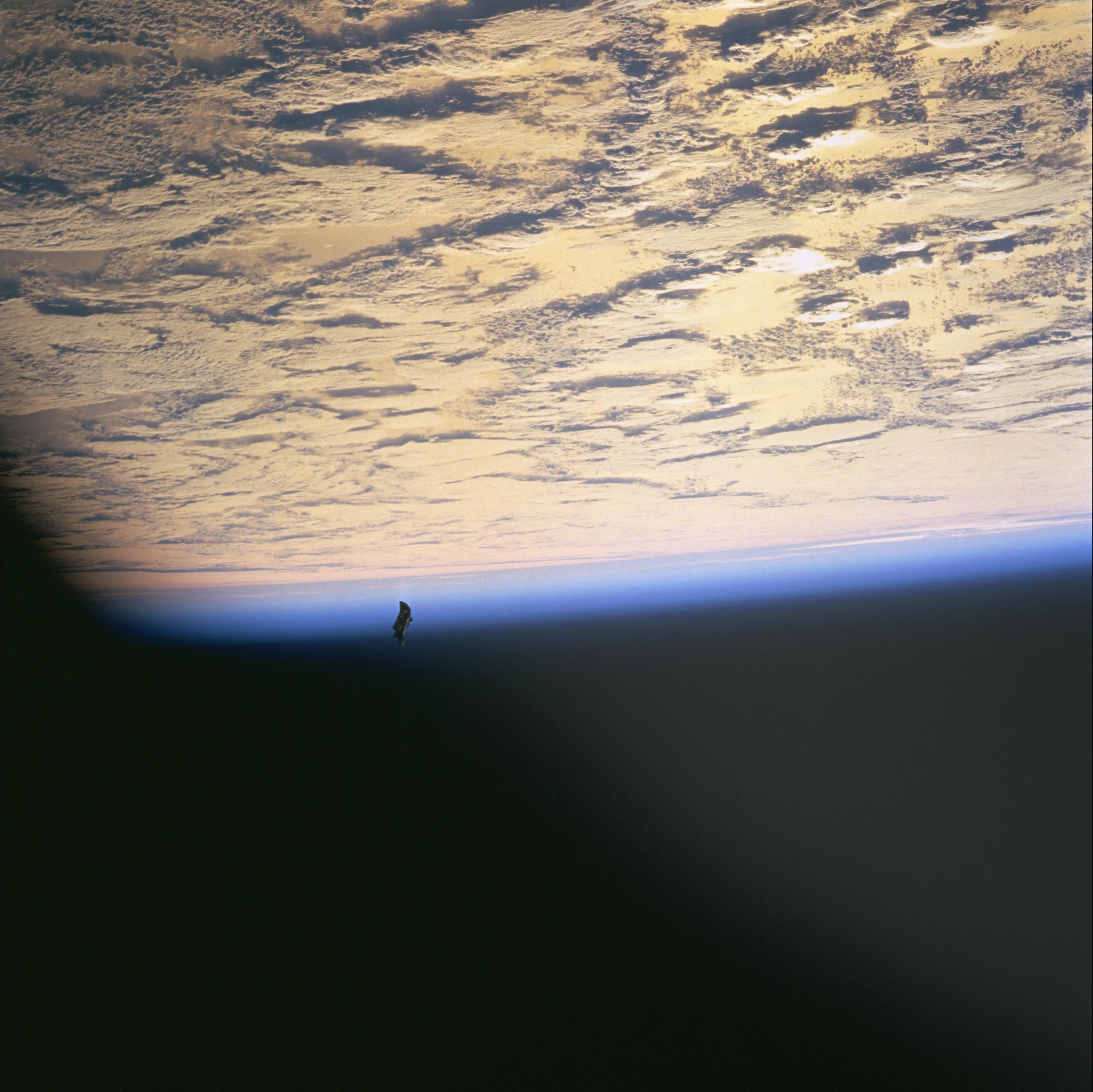 Small irregular dark debris near Earth's blue limb and cloud cover in NASA frame STS088-724-66