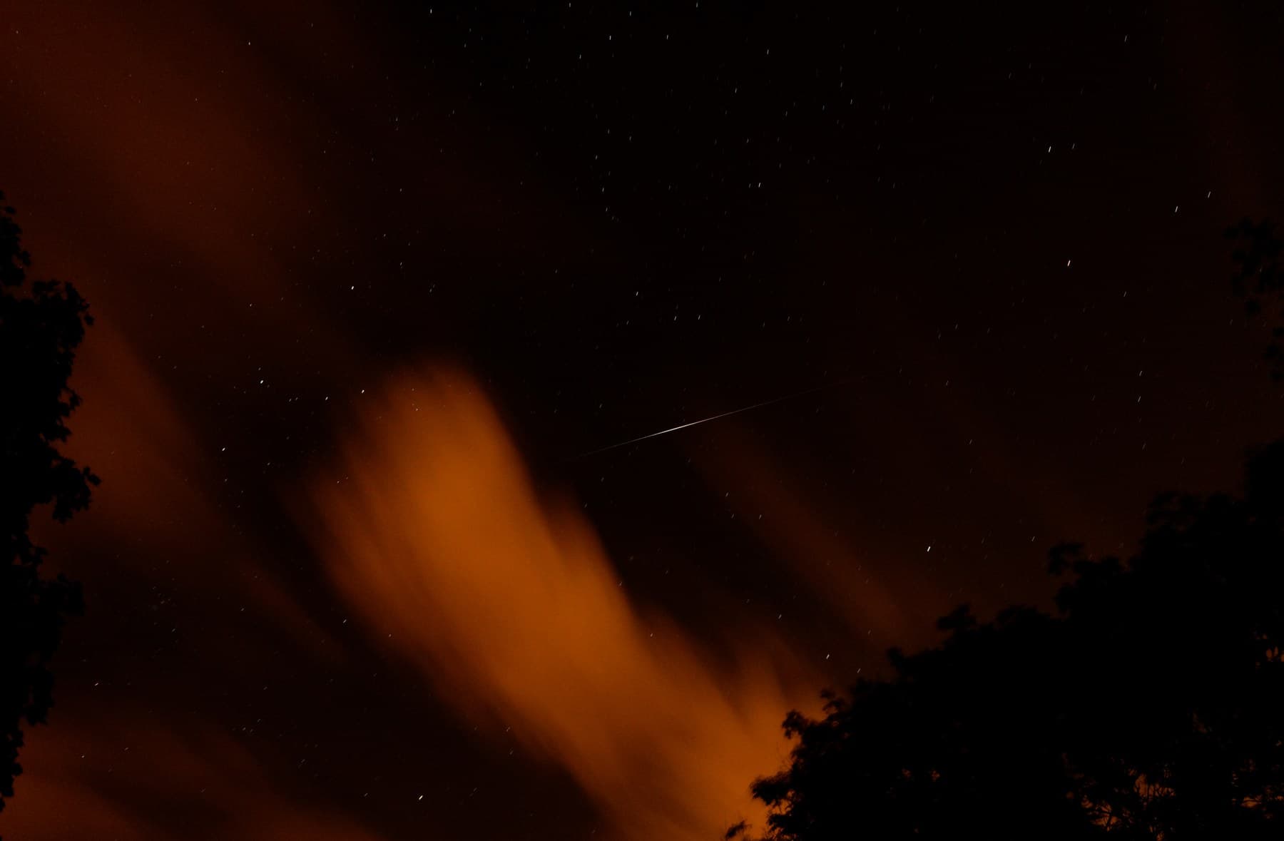 铱星闪光划过多云夜空的长曝光照片