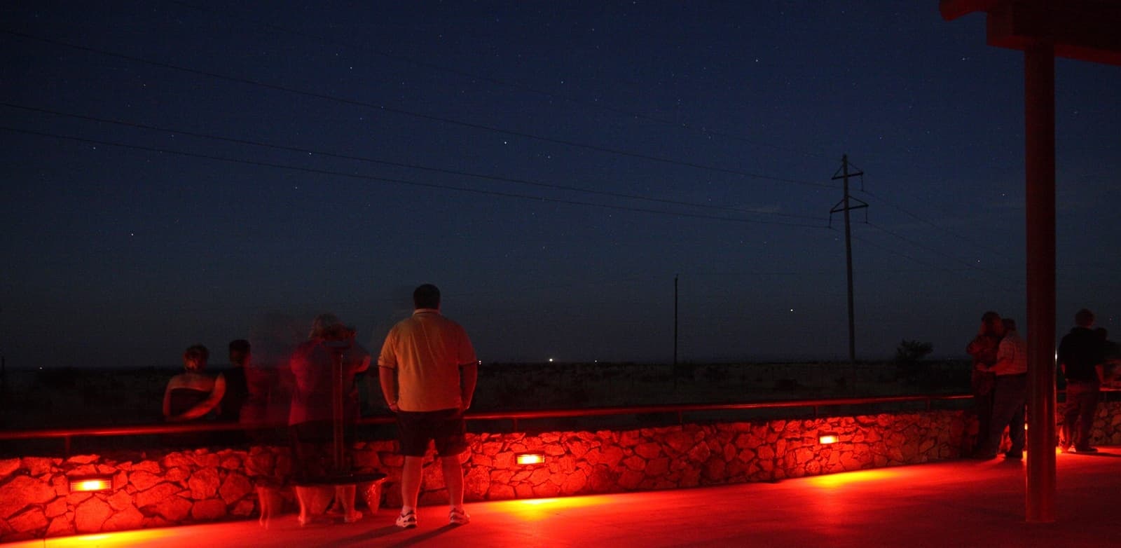 Visitantes en el área de observación de Marfa Lights con una luz distante cerca del horizonte