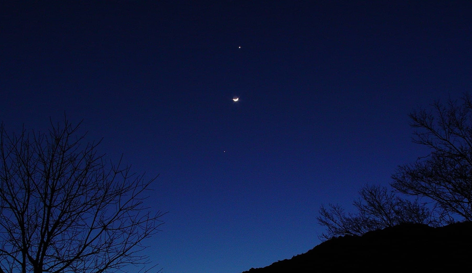 Crescent Moon with Venus and Jupiter visible as bright points in the evening sky